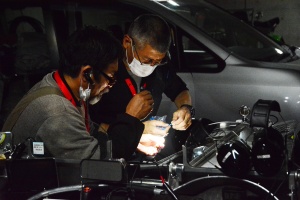 Mechanics maintaining cars until late at night everyday. They help each other to fix cars they are not in charge